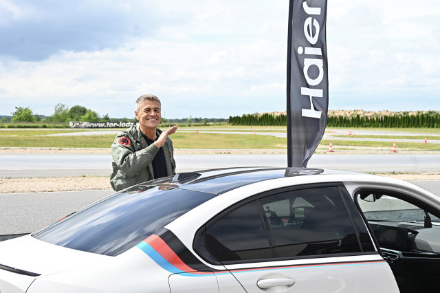 Krzysztof Hołowczyc ambasador marki Haier na torze wyścigowym podczas premiery nowych telewizorów, w otoczeniu sportowych emocji i motoryzacji.
