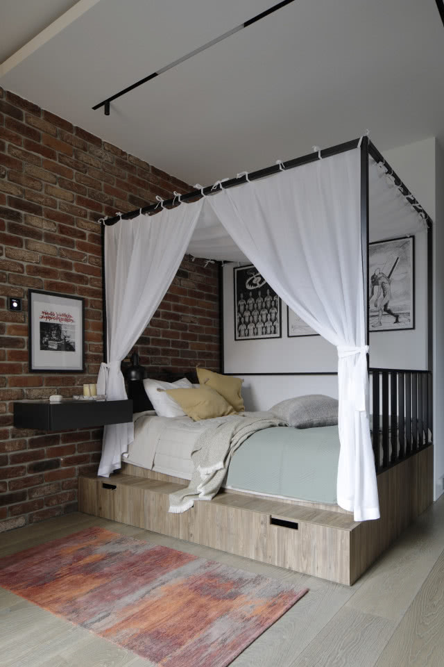 Sypialnia z cegłą na ścianie i baldachimem na łóżku
