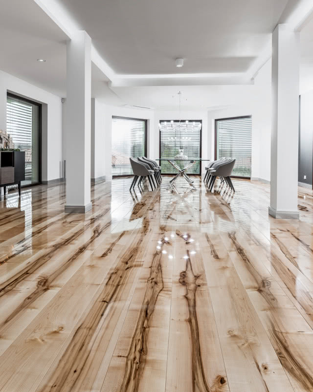 podłoga lakierowana z wyraźnymi sękami i słojami, duży stół z krzesłami w jadalni