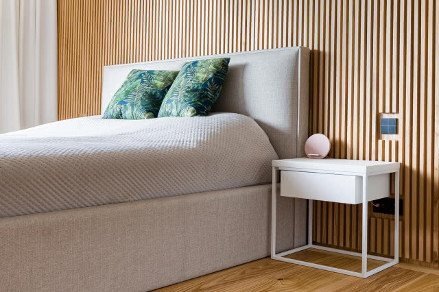 duże łóżko, lamele na ścianie, deska podłogowa, stolik nocny, poduszki ozdobne, kontakt, zasłony