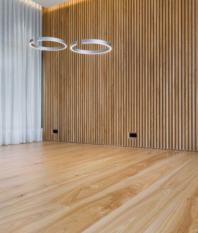 lamele na ścianach, drewniana podłoga, telewizor, oświetlenie sufitowe, zasłony, kontakty