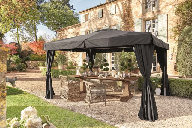 czarny namiot, tkanina związana po bokach, pod nim modne meble 