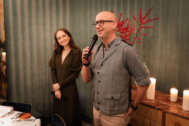 Marcin Oleszczuk z Kontakt-Simon przemawia podczas spotkania z architektami, trzymając mikrofon na tle nowoczesnego wnętrza.