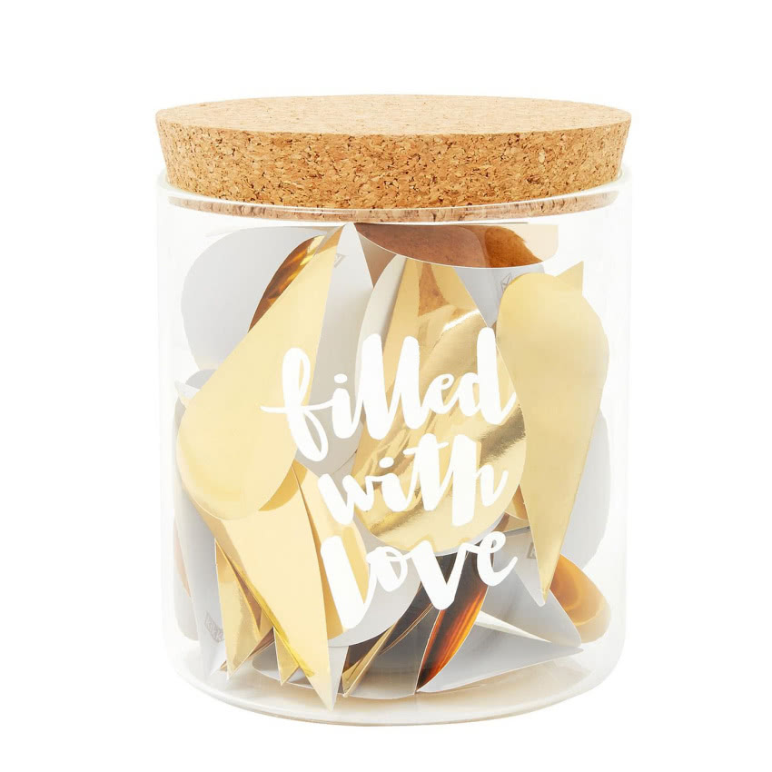 Słoik wypełniony złotymi serduszkami, a w...