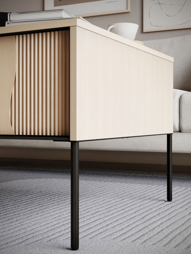 Detal komody z jasnego drewna na smukłych czarnych nóżkach, ryflowany front w stylu mid-century w nowoczesnym wnętrzu