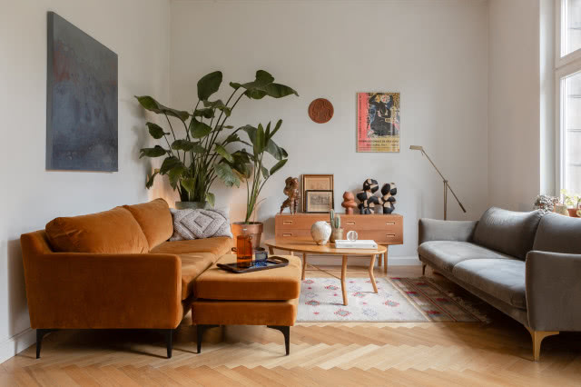 Vintage salon z jodełką francuską na podłodze i pomarańczową kanapą