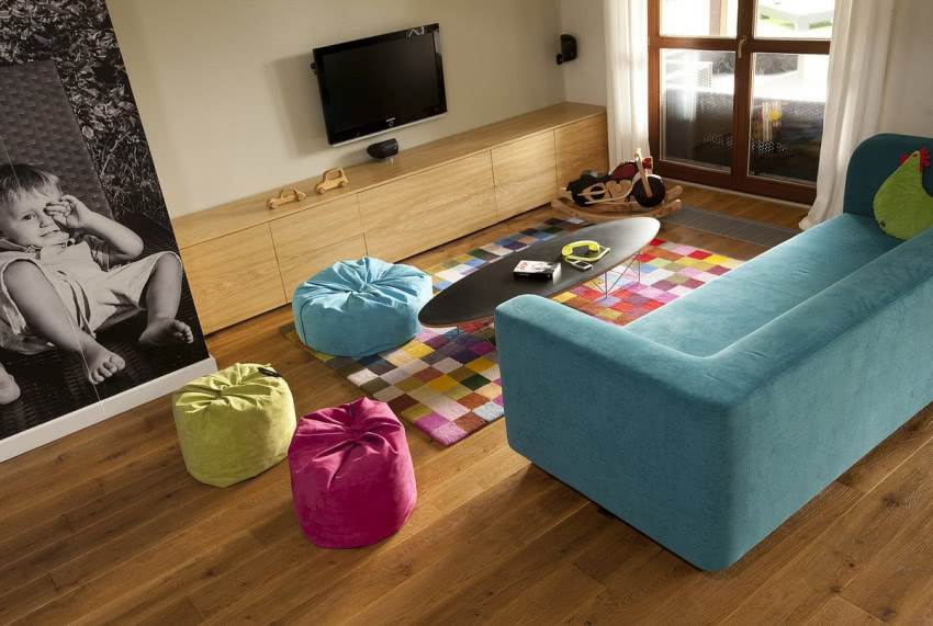 Kolorowa sofa i pufy w salonie sprawiają, że...