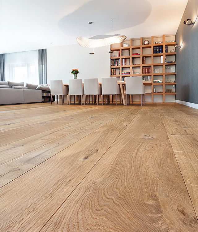 jasna podłoga drewniana, półki na książki, stół z krzesłami, kanapa