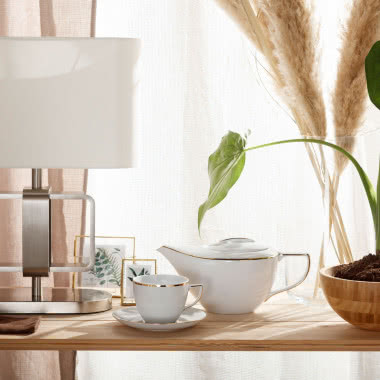 filiżanka, czajniczek, lampa biurkowa, ramki na zdjęcia, kwiat w doniczce, drewniany stół