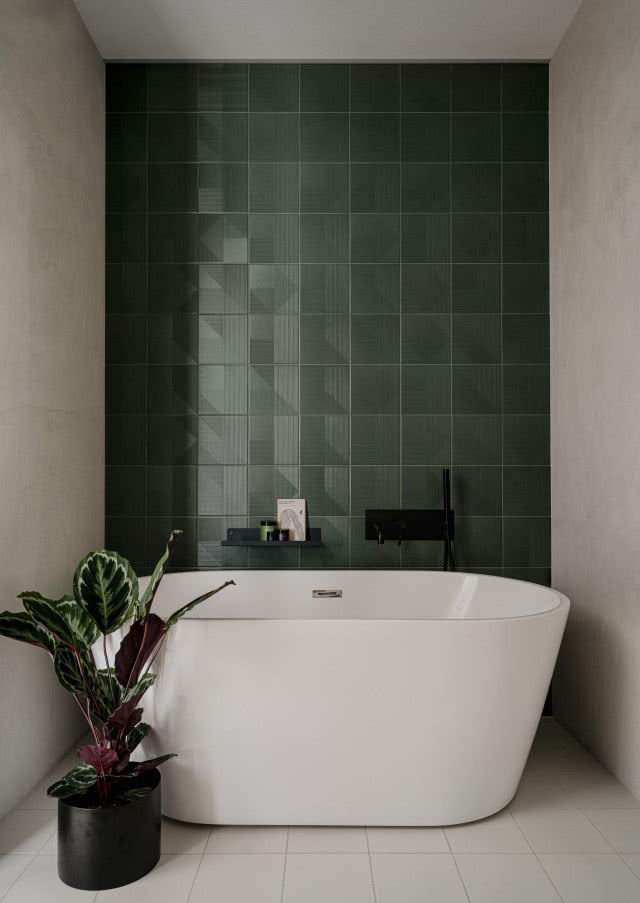 ciemnozielone płytki w łazience na tle wolnostojącej wanny