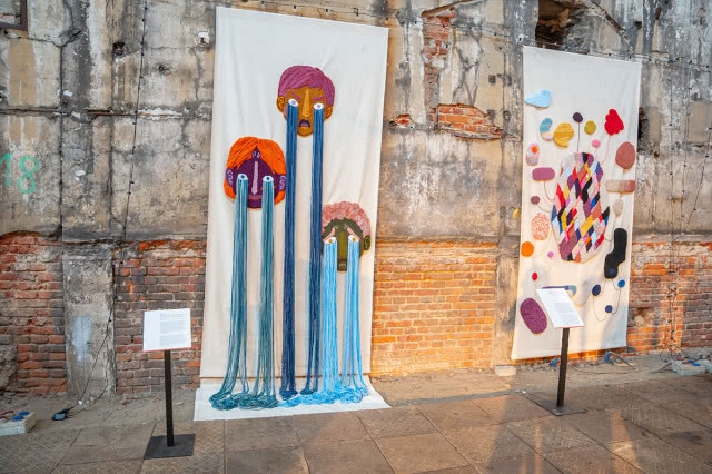 Kolorowe instalacje artystyczne z włóczki i tkanin prezentowane na wystawie w industrialnej przestrzeni podczas Łódź Design Festival.