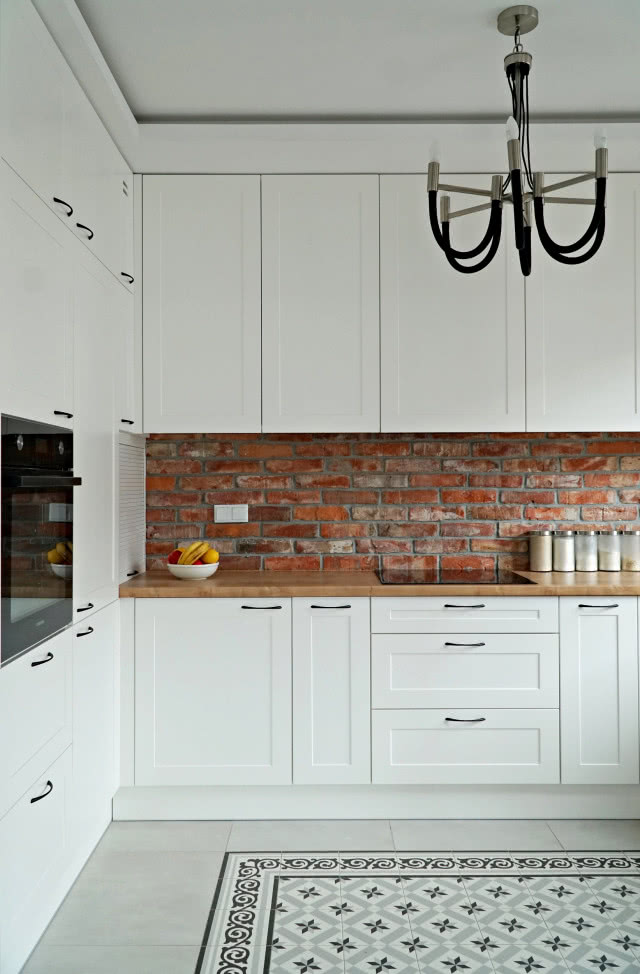 Biała kuchnia z czerwoną cegłą.