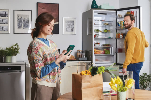 lodówka, artykuły spożywcze w lodówce, Kobieta z telefonem sterująca aplikacją