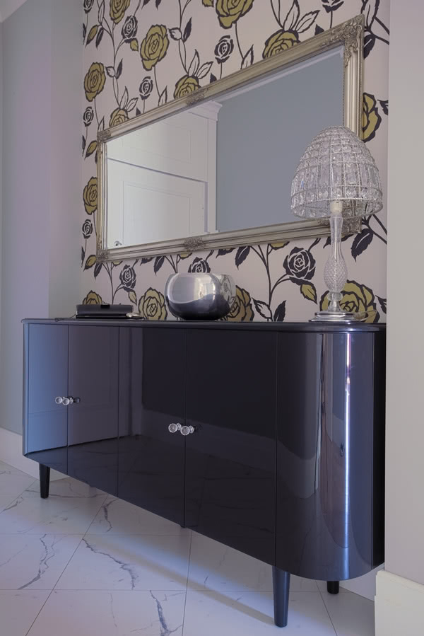 Błyszczącą komodę w przedpokoju ustawiono na tle...