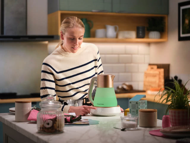 Pani wstawia wodę w czajniku, wyspa kuchenna