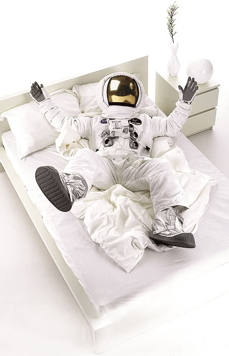 kosmonauta, kołdra, duże łóżko w sypialni, stolik nocny, wazony