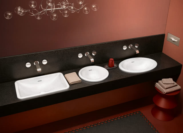 umywalka prostokątna, umywalka okrągła i umywalka owalna wpuszczana w blat, baterie podtynkowe, czarny blat, stołek ręczniki, oświetlenie sufitowe