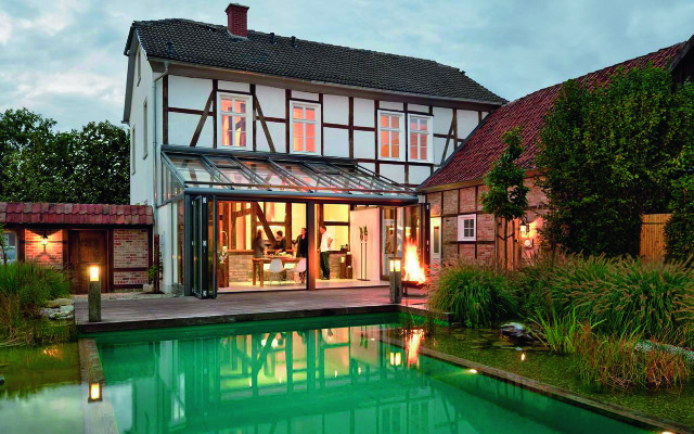 Ogród zimowy oparty o ścianę
domu, z jednospadowym dachem
i pięknym widokiem na połyskliwą
wodną taflę