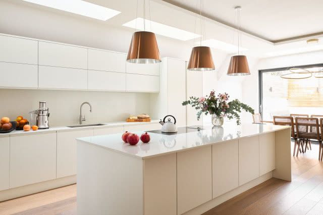 kuchnia cała biała z trzema wiszącymi lampami nad wyspą
