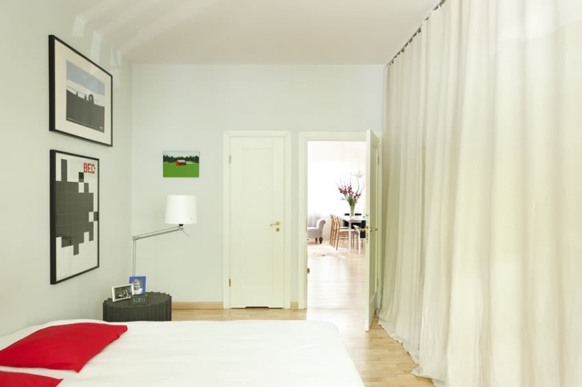 Za lnianą tkaniną kryje się w sypialni garderoba.