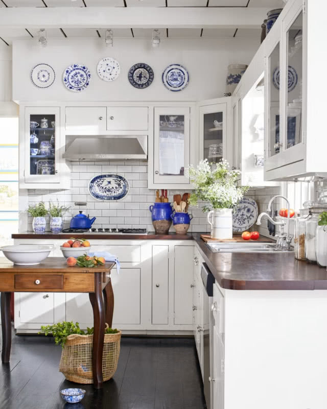 biała kuchnia z niebieskimi talerzami dekoracyjnymi