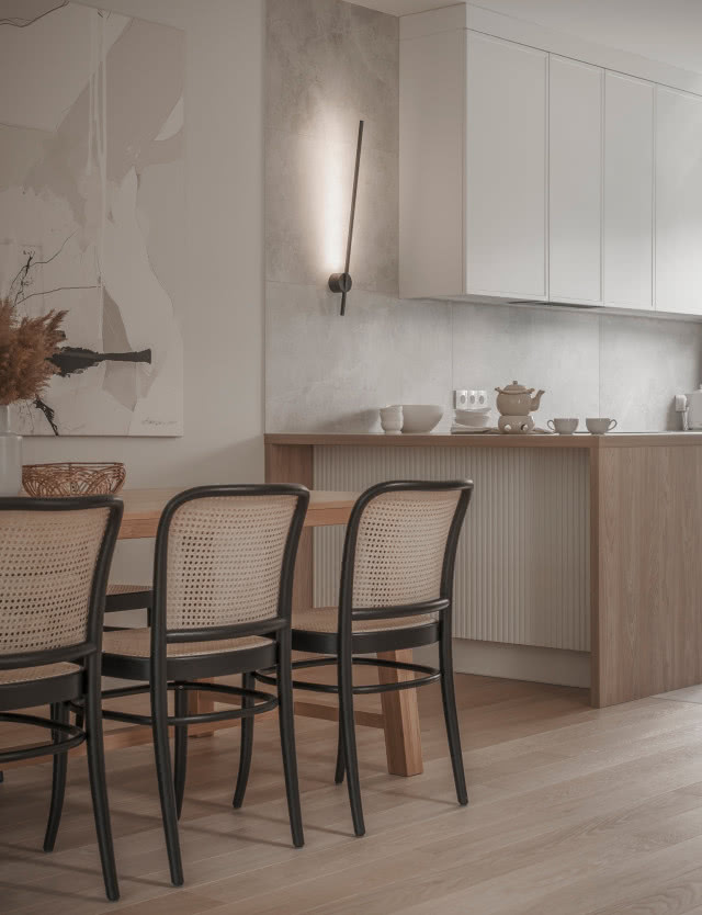 duży stół z krzesłami, obraz, półwysep, filiżanki, czajniczek porcelanowy, białe szafki wiszące, drewniana podłoga