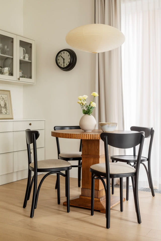 Drewniany stół okrągły w jadalni z czarnymi krzesłami i lampą nad stołem