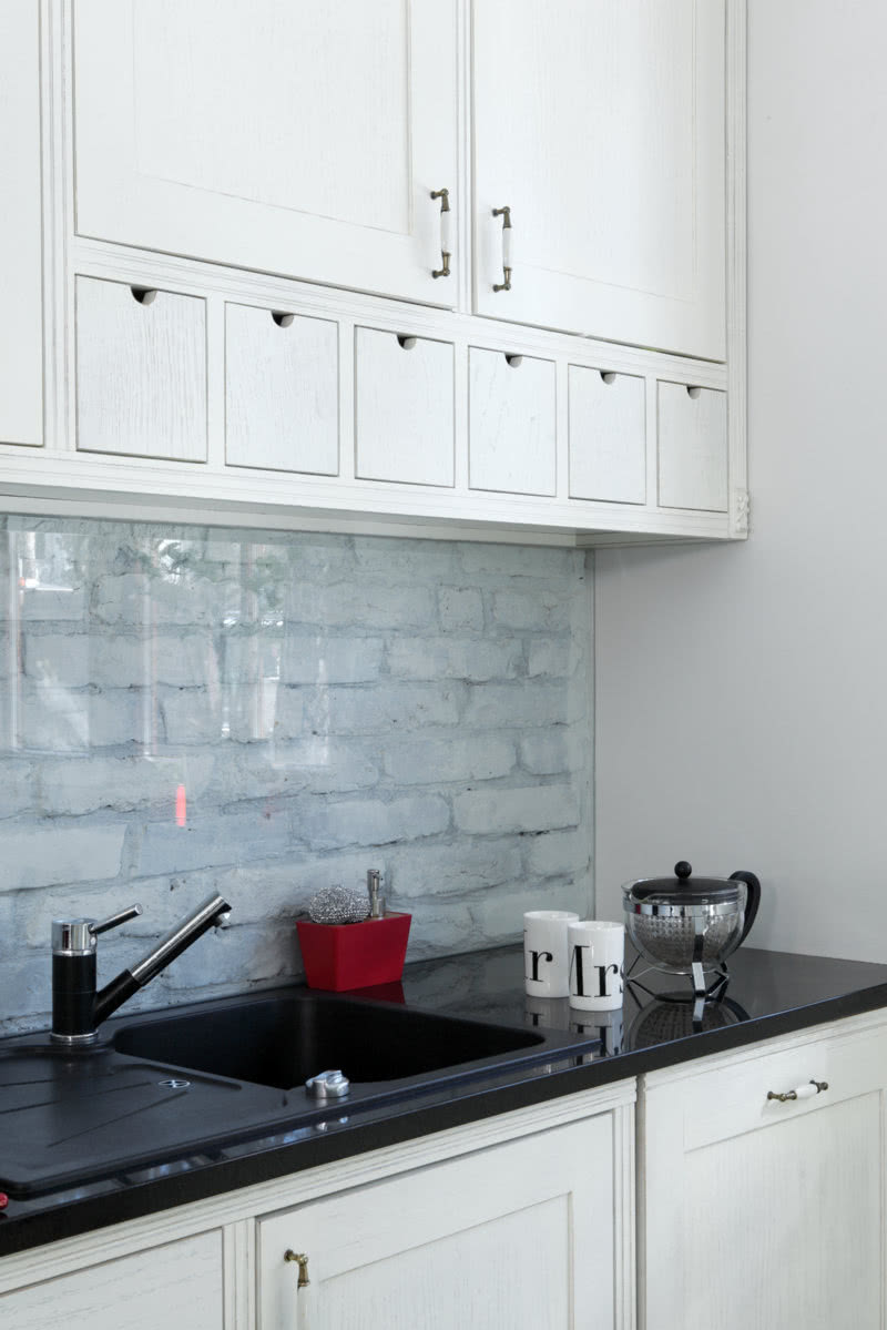 Ścianę nad kuchennym blatem wyłożono ce3głą z...