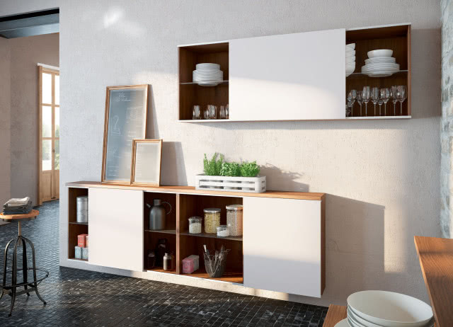 Bezuchwytowe otwieranie szafek, szafki wiszące z białymi frontami kuchennymi, obrazy, przyprawy, produkty spożywcze, stołek barowy, talerze, kieliszki, szklanki, zioła w białej skrzynce, drewniane blaty