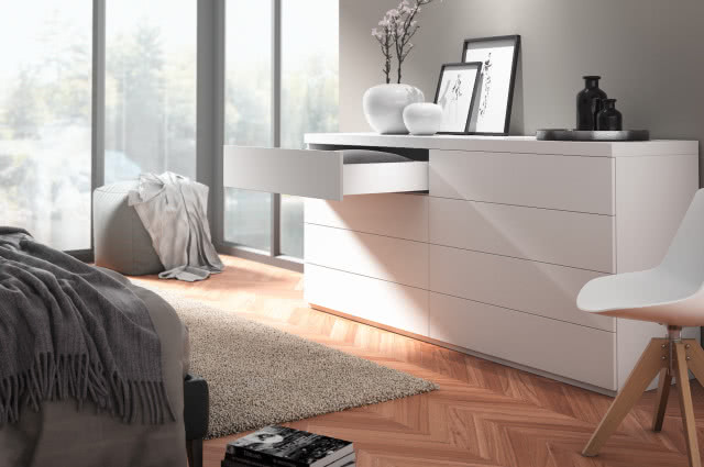 Bezuchwytowe otwieranie szafek, Fronty / meble bezuchytowe - System Push to Open i Push to Open Silent, komoda, krzesło obrotowe, wazon z kwiatami, narożne duże okno, obrazy, puf, koc, dywanik, jodełka na podłodze, kiążki 