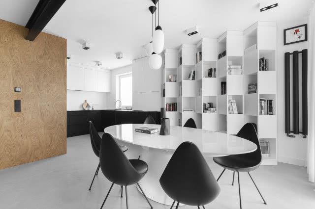 Biało-czarny salon z aneksem kuchennym i betonową podłogą