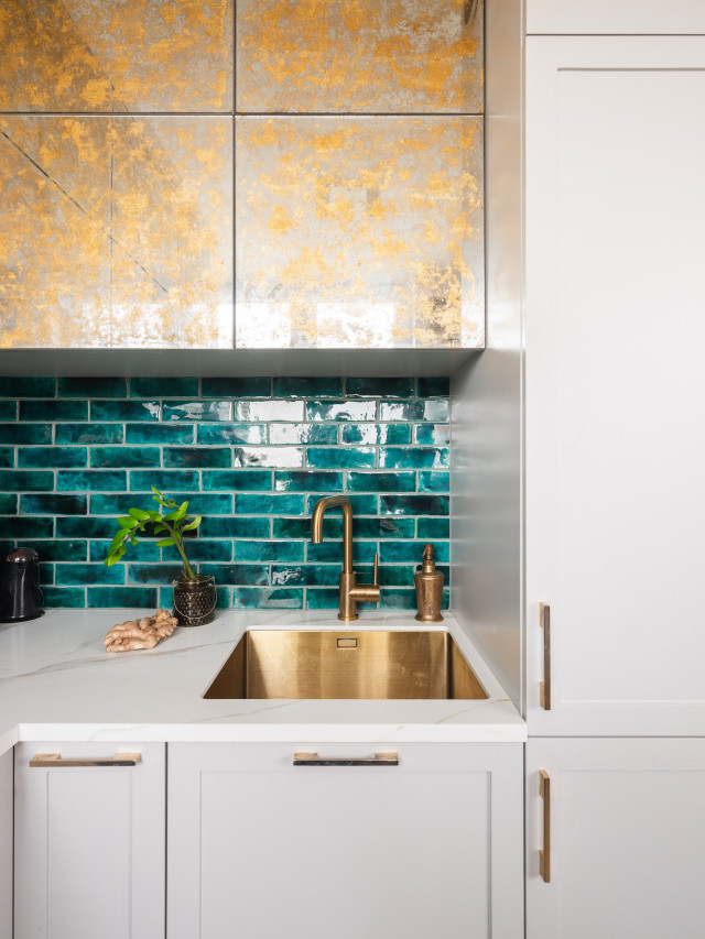 Złote szafki w kuchni i szkliwione płytki