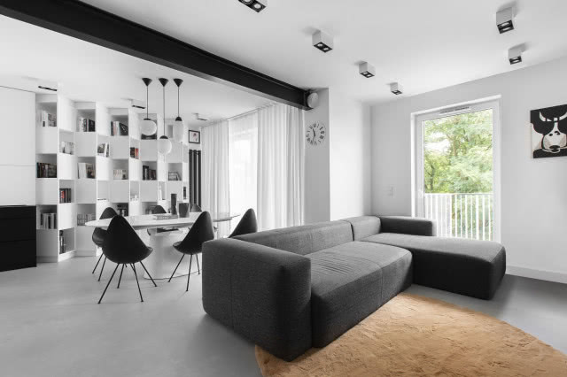 Biało-czarny salon z betonową podłogą i karmelowym dywanem