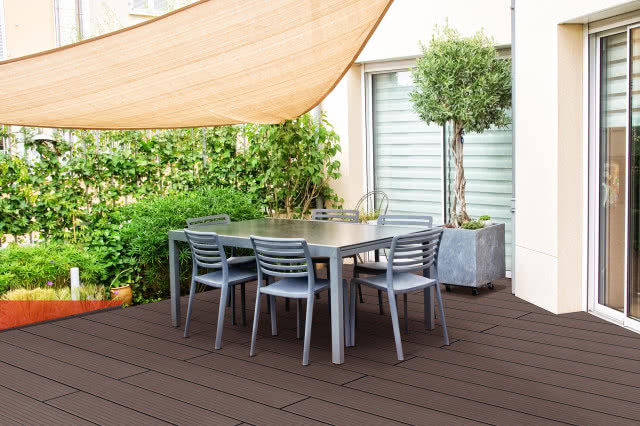 stół i krzesła na tarasie, który chroni żagiel przeciwsłoneczny