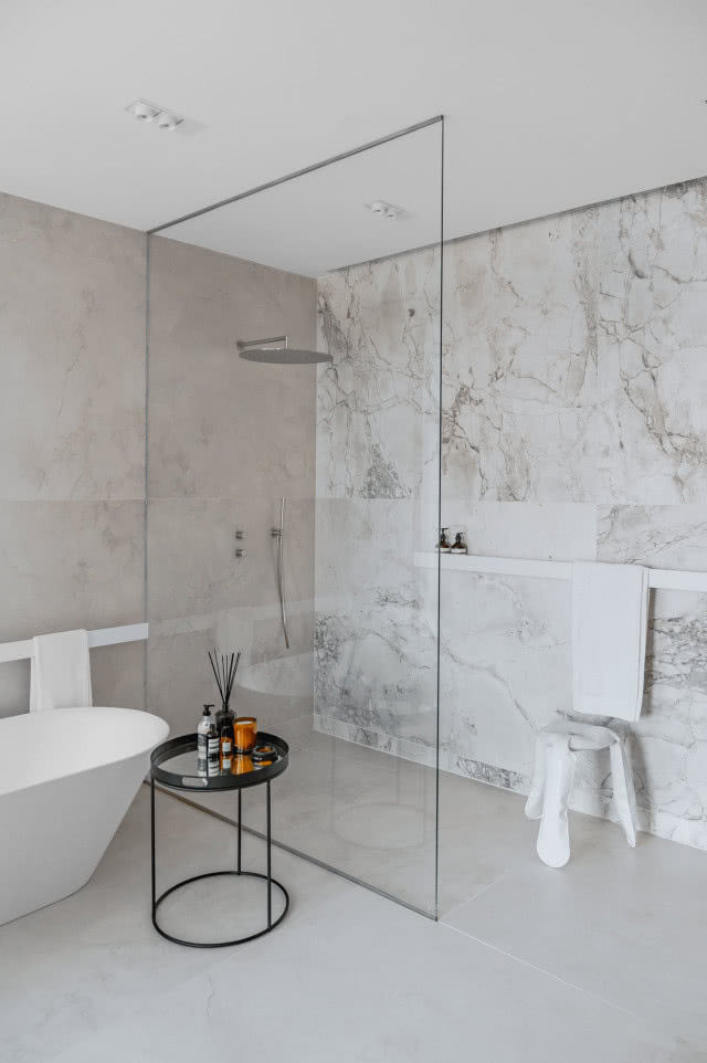 Podłogi i ściany łazienek zostały wykończone spiekami imitującymi kamień naturalny. Jasna tonacja sprawia, że całość jest lekka wizualnie i elegancka.