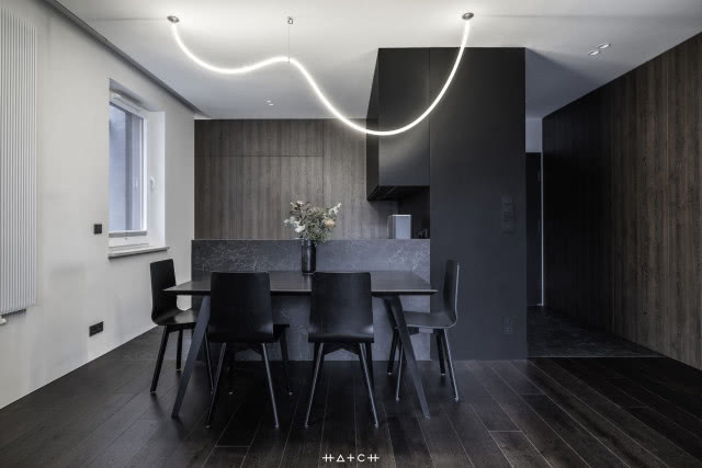 czarne meble kuchenne, czarny spiek kwarcowy, duży stół z czarnymi krzesłami, grzejnik, wyspa kuchenna