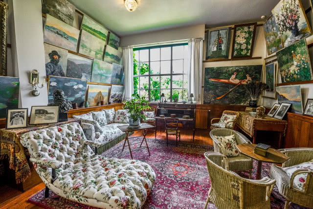 pokój z kanapą, fotelami wiklinowymi i obrazami