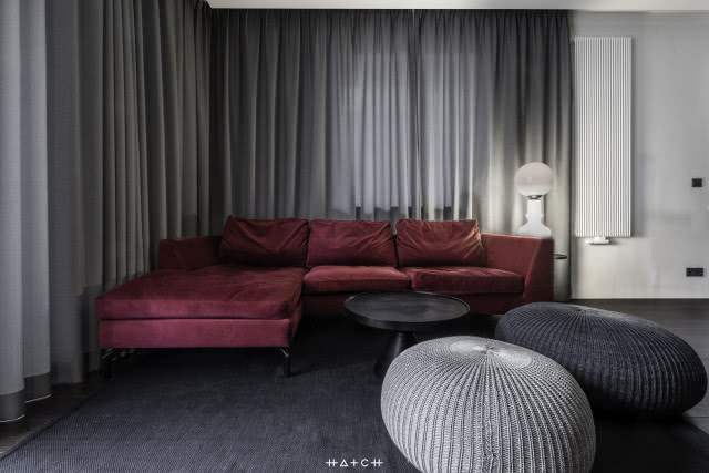 bordowa kanapa, szare pufy, szare zasłony, grzejnik, lampa biurkowa, dywan stolik kawowy