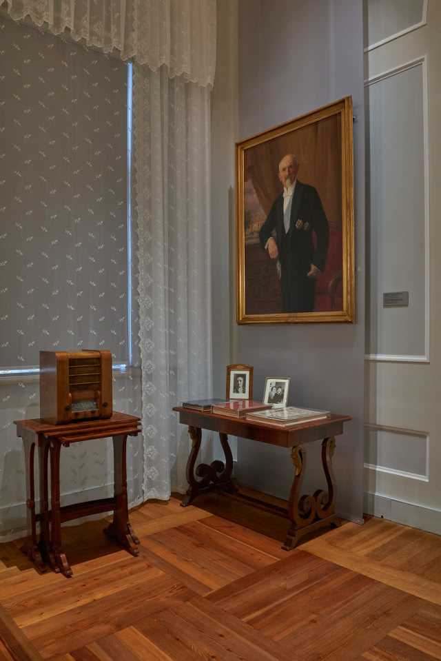 konsola z zegarem i portret na ścianie