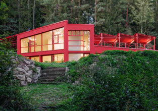 Czerwony dom w środku lasu. Stalowa elewacja robi wrażenie