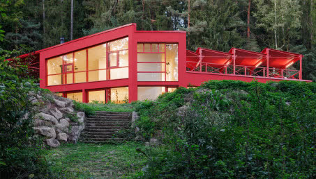 Czerwony dom w środku lasu. Stalowa elewacja robi wrażenie