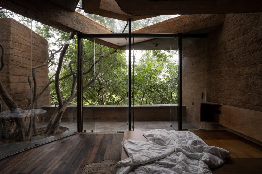 Duże okna w sypialni oferują widok na zieleń.