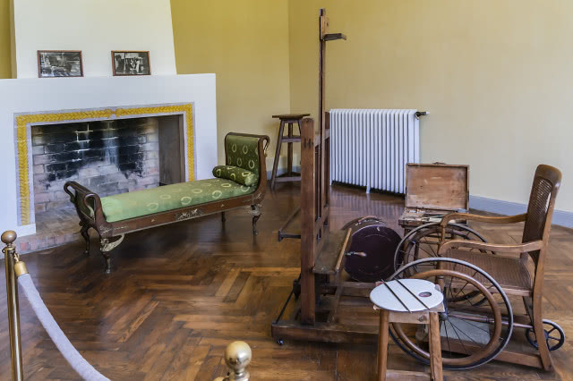 pokój w muzeum, na pierwszych planie wózek inwalidzki i sztaluga