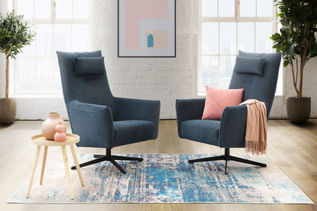 dwa granatowe fotele, poduszka ozdobna, koc, stolik kawowy, wazony, obraz, dywan, kwiaty w doniczkach