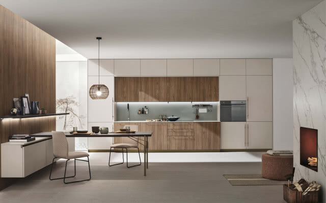 białe i drewniane fronty kuchenne, piekarnik, lodówka, komoda,, półka na zdjęcia, stół z krzesłami, kominek, drewno kominkowe, stolik, oświetlenie sufitowe