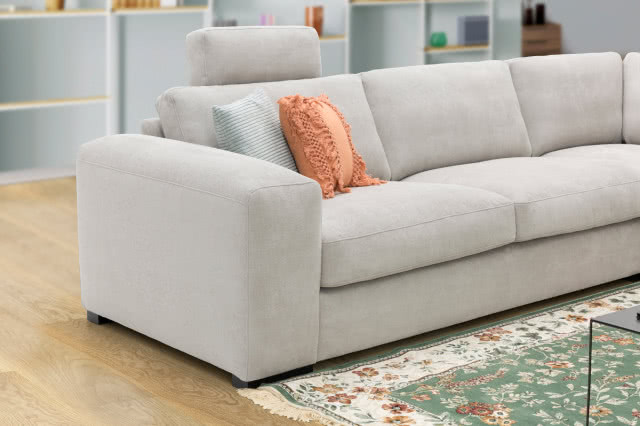 szara kanapa, poduszki ozdobne, dywan, stolik kawowy, półki