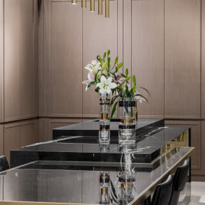 Kuchnia, stoły z czarnego marmuru z białym użyleniem oraz szklanym blatem ze złotymi wykończeniami