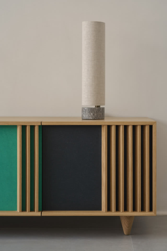 lampa na marnurowej podstawie stoi na zielonej komodzie