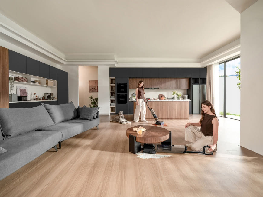 Odkurzacz myjący Tineco Floor One S7 Max Gold usuwa rozlane zabrudzenia na drewnianej podłodze w nowoczesnym salonie z kuchnią.