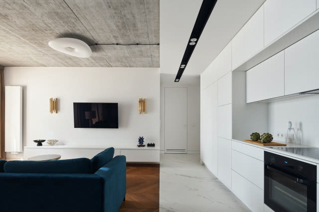 Betonowy sufit w mieszkaniu z białą kuchnią